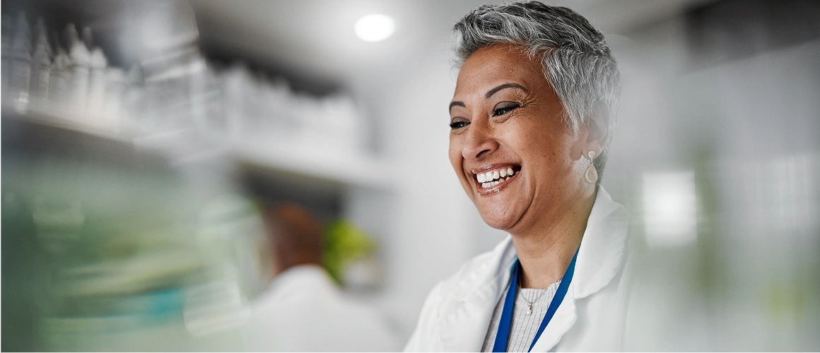 Smiling professional in a lab coat, embodying success through BeOne Careers.