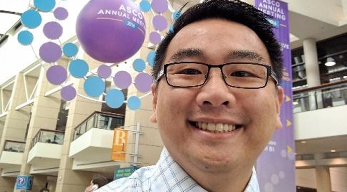 Danny Lu smiles at the ASCO Annual Meeting, engaging in discussions about cancer care advancements.