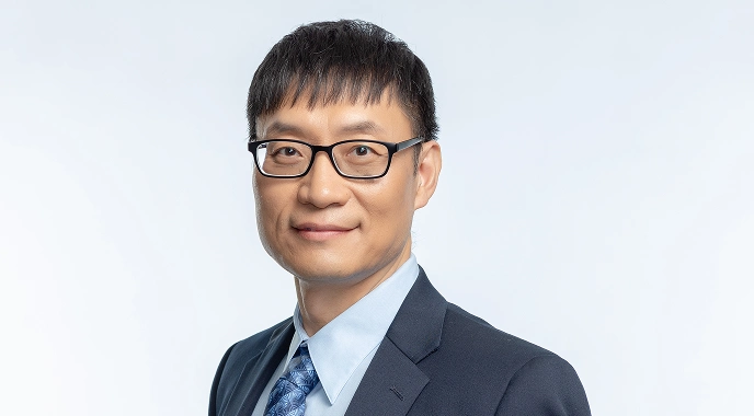 Dr. Zhiwei Wang glasses and a suit smiles confidently, representing professionalism and dedication in cancer care.